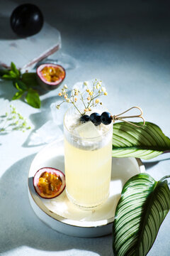 Drinks and cocktails. Alcoholic yellow cocktail with passion fruit, plum and ice. Sunshine, summer, flowers. Tropical concept. Green leaves. Background image, copy space, bar menu