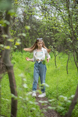 Naklejka na ściany i meble fashionable little teen girl in the forest, through the green branches of the trees with hay