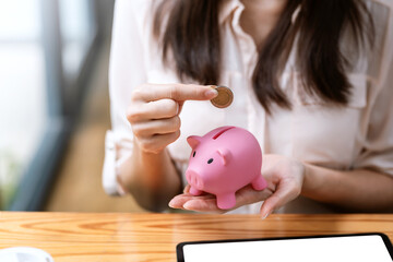 Obraz na płótnie Canvas Close-up of woman hand putting coins in a piggy bank saving money concept.