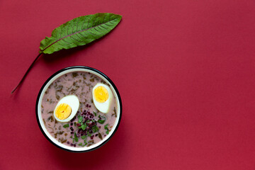 Sorrel soup with halved egg in enamel bowl. Flat lay top view.