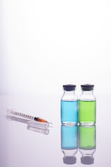 close-up vaccine. Glass vials with multi-colored liquid and a syringe, on a white background.
