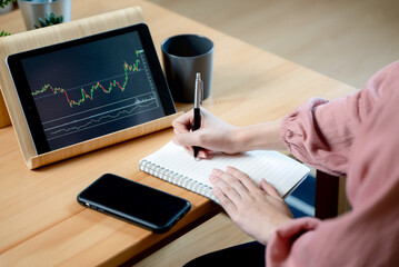 stock trade at home.  Close up hand of person learning and analyzing the chart of stock market via application