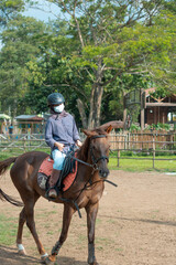 Women with mask and hijab learns to ride a horse. girls riding horses at the ranch. equestrian sport during the pandemic