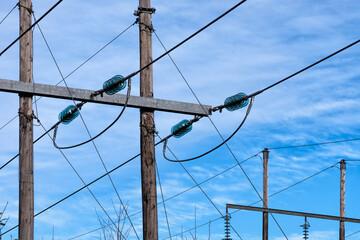 Power supply line with three wires mounted on old wooden pillar, blue sky with soft white clouds at...
