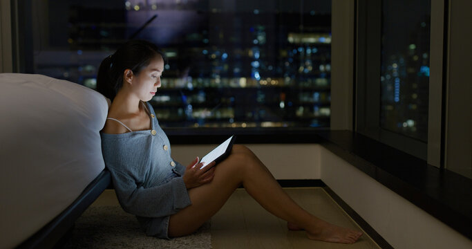 Woman work on tablet computer beside window at night
