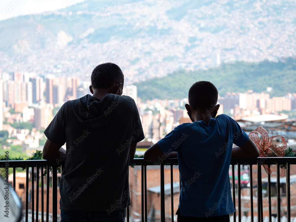 Wall mural children leaning on the railing of a terrace contemplating the view of commune 13, a tourist neighbo