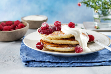 Pancakes for breakfast with sour cream, raspberry jam and fresh raspberries.