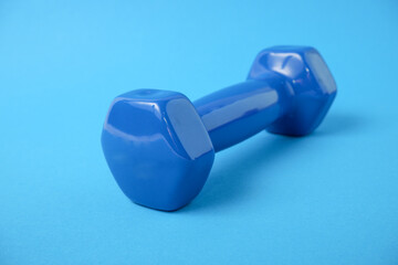 Dumbbells in a plastic sheath on a blue background. Sports inventory. Training workout equipment. Sport and exercises.