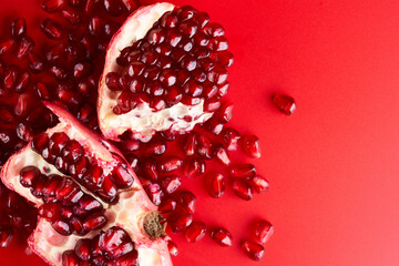 Ruby ripe fresh juicy sliced pomegranate isolated on red background