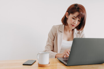 Asian working woman is using laptop on the office desk with white background.