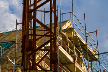Scaffolding and crane around the house roof on blue sky background