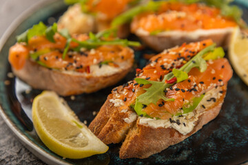 delicious bruschetta with salmon avocado and arugula on a large blue plate.