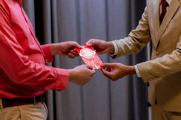 Chinese New Year and people giving red envelope with blessing words contained money as a gift. The...