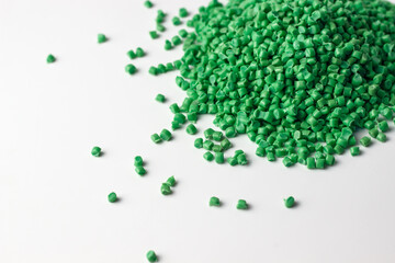 Green granules of polypropylene or polyamide on a white background. Plastics and polymers industry. Copy space. 