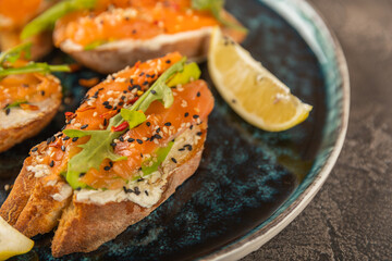 delicious bruschetta with salmon avocado and arugula on a large blue plate.