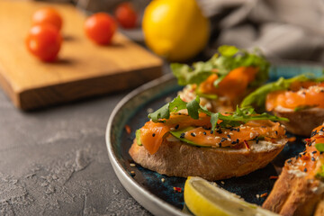 delicious bruschetta with salmon avocado and arugula on a large blue plate. copy space