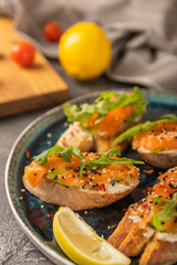 delicious bruschetta with salmon avocado and arugula on a large blue plate.