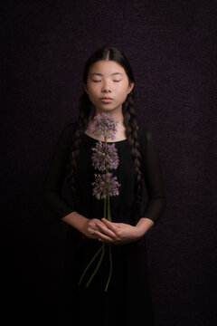 Classic painterly portrait of asian girl in black dreaming with braids and purple flower