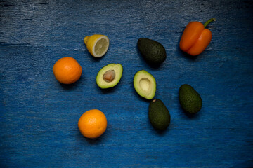 Fototapeta na wymiar Fruits and vegetables on the blue wooden background. Oranges, avocado, pepper, lemon.