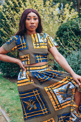 Beautiful African black woman walking in park. Pretty young woman with brown skin. Strong black woman with wearing African print crop top and skirt in a tribal pattern.
