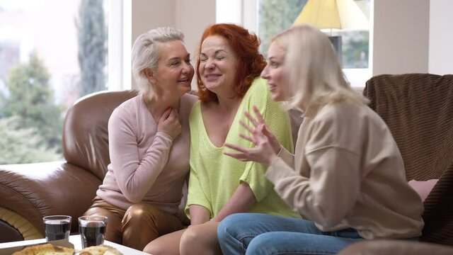 Surprised excited Caucasian woman sitting at home with friends sharing rumors talking. Portrait of beautiful lady looking at camera with shocked facial expression as women gossiping. Lifestyle concept
