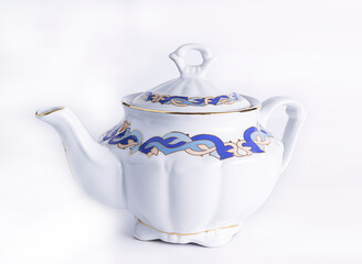 White porcelain teapot with a blue-gold pattern on a white background. Isolated background