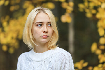 young blonde with freckles short haircut white sweater in autumn