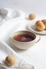 Black tea in a mug on the table. Nearby are croissants, a towel and nuts. Breakfast