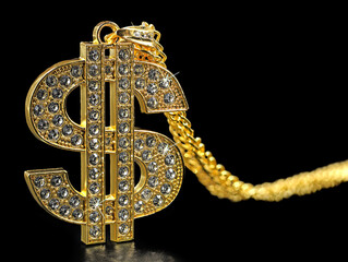 golden necklace dollar symbol with sparkling diamonds isolated on black background, close up