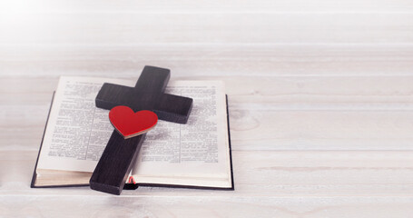 Cross. Open Bible. Holy Bible. Red heart. On a wooden table.