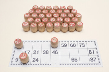 Card for playing lotto or bingo and many wooden barrels with numbers. Board game. Interesting fun pastime.