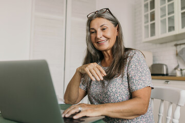 Good-looking, charming grand-mother having online video conversation with her daughter and...