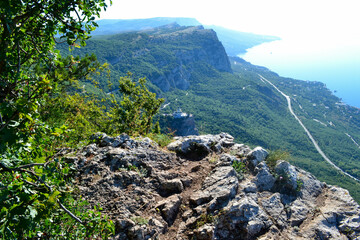 Majestic view on a sunny day from a mountain plateau to a green coastal town and a small church by the sea