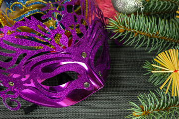 Purple mask, fir branches and decorations.