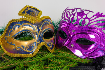 Golden and purple Venetian masks on fir branches on a white background.