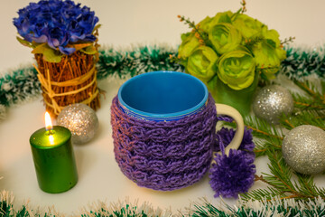 Obraz na płótnie Canvas Burning candle and knitted mug with pompoms.