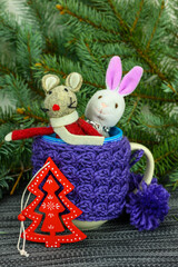 The rat and the hare look out from the knitted mug.