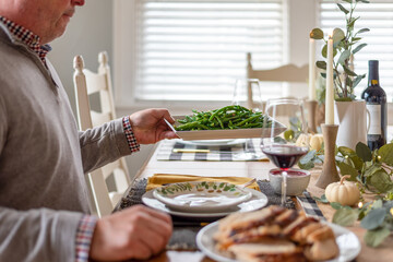 Man passing a plate of green beans at the dinner table