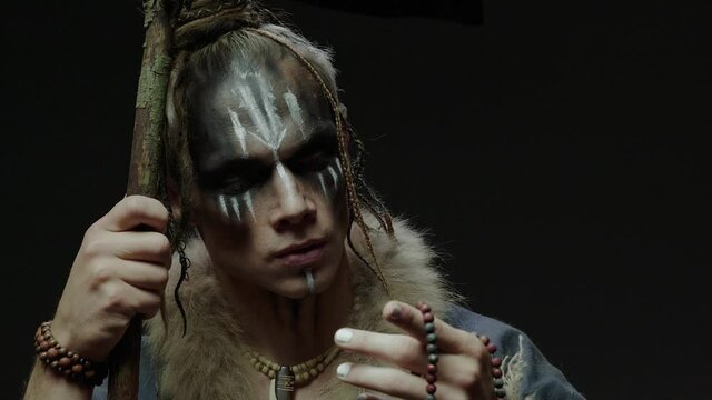 Young druid magician fingers rosary and leans on stick