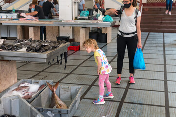 Curious girl looking at fish catch at local market.