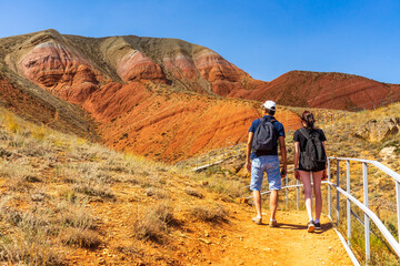 Family couple travelers walking in mountain area. Rear view of man and woman standing on trail...