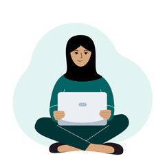 A woman in a black headscarf sits and works at a laptop. Muslim. Remote work or communication over the Internet. - obrazy, fototapety, plakaty