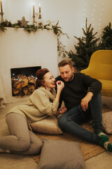 Naklejka premium Happy charming woman dressed in knitwear talking to her handsome boyfriend spending time at cozy home 