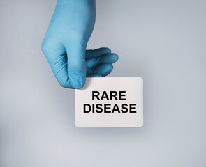 Rare disease concept. Text on white paper in hands in blue gloves.