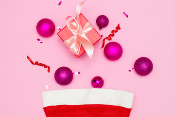 Christmas composition. A Christmas red hat made of fireworks made of balls, sequins, ribbons on a pink background. Flat layout, top view, place to copy.