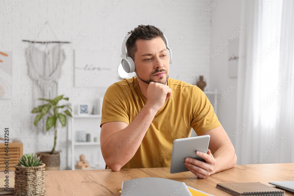 Poster man with tablet computer and headphones at table