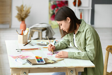 Young female artist painting in workshop