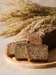 A loaf of sourdough rye bread and a few sliced ​​slices on a wooden board. Vertical format.