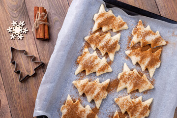 Raw Christmas tree shaped puff pastry cookies with sugar and cinnamon, ready to bake, closeup