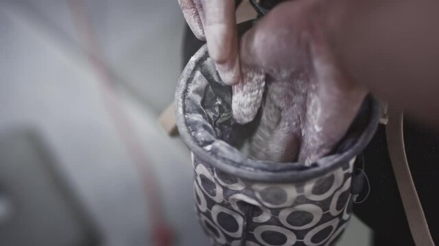 Closeup Sports athletic girl rock climber uses magnesium in a cloth bag, dips her hand and palm into powder. Climbing in the gym. Practicing Solo Climbing on Bouldering Wall in Gym.
